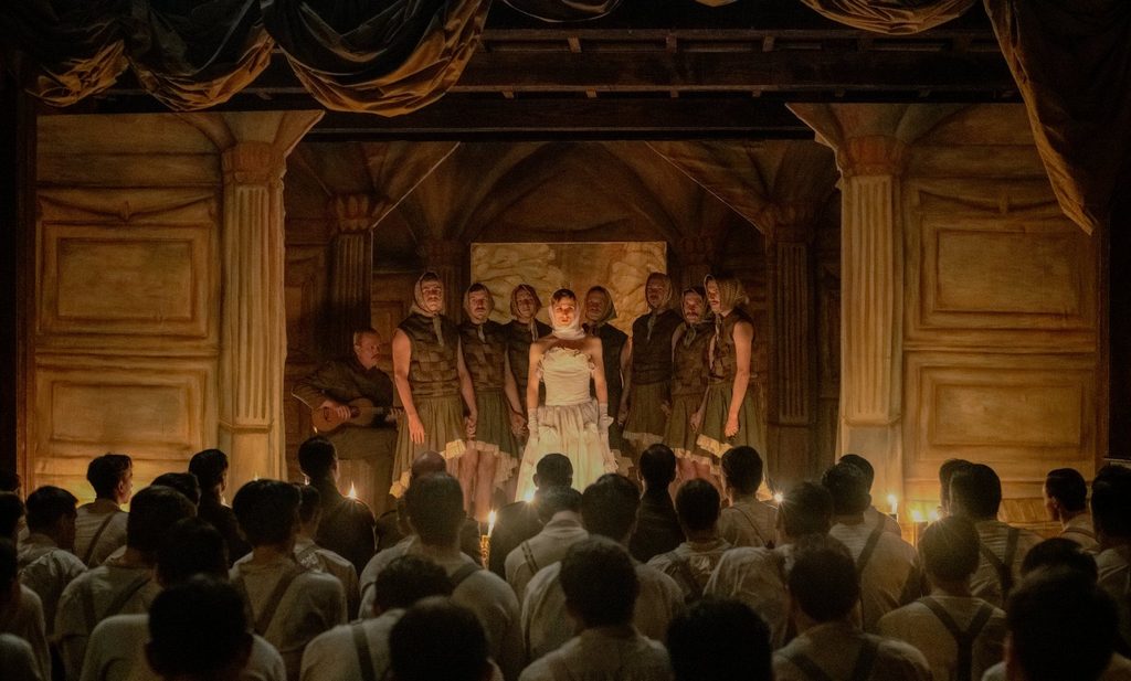 Revue théâtrale aux chandelles jouée par des soldats en costumes de scène dans Coward de Lukas Dhont